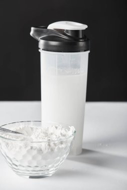 Spor şişesinin yanında protein kasesi ve siyah protein karışımı. 