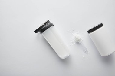 Spor şişesinin yanındaki kavanozun üst görüntüsü ve beyaz proteinli kaşık. 
