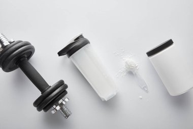 Dambıl yanında protein bulunan kaşık üst görünümü ve beyaz üzerine spor şişesi 