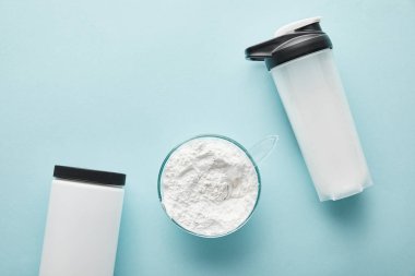 Kavanoz ve cam kasenin yanındaki spor şişesinin üstünde mavi protein tozu var. 