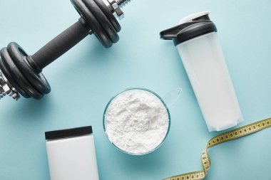 Spor şişesinin yanındaki ağır dambılın ve mavi bandın üst görüntüsü. 