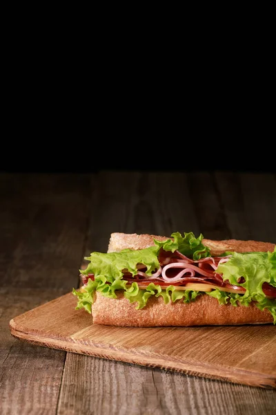 レタス チーズ ベーコン トマトの新鮮なサンドイッチ木のまな板に黒で隔離された — ストック写真