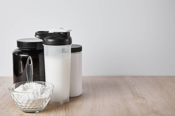 sports bottle with protein shake near jars isolated on grey