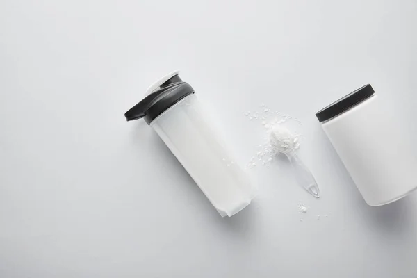在运动瓶和勺子附近的罐子顶部 白色上有蛋白质 — 图库照片