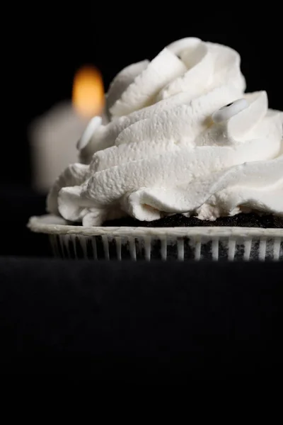 美味的万圣节纸杯蛋糕 白色奶油和模糊的蜡烛 背景与黑色隔离 — 图库照片