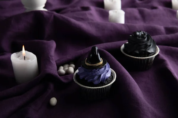 Вкусные Кексы Хэллоуин Возле Горящих Свечей Фиолетовой Ткани — стоковое фото