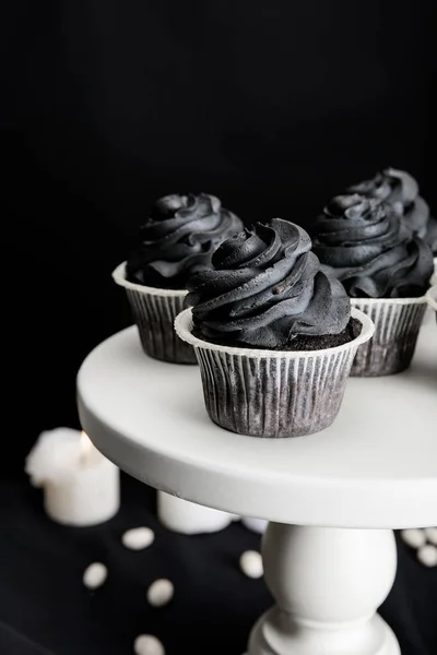 精美的万圣节纸杯蛋糕 上面放着黑色奶油 旁边点着用黑色隔开的蜡烛 — 图库照片
