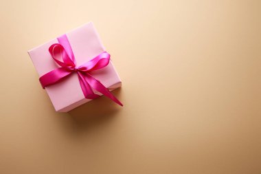 Bej arka planda kurdeleli pembe hediye kutusunun üst görünümü