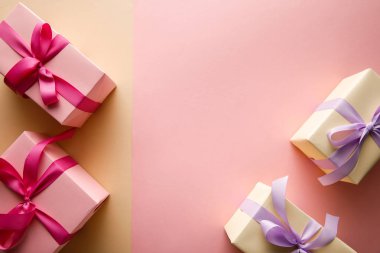 Pembe ve bej arka planda kurdeleli hediye kutularının üst görünümü