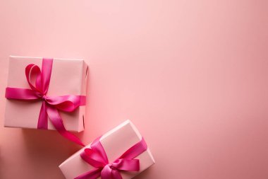 Pembe arka planda saten kurdeleli hediye kutularının üst görünümü