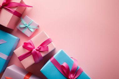 Pembe arka planda saten kurdeleli renkli hediye kutularının üst görünümü
