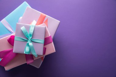 Renkli hediye kutularının üst görünümü kurdeleli ve mor arkaplanlı ve kopyalama alanı olan fiyonklar