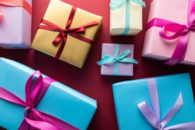 top view of colorful gift boxes with ribbons on red background clipart