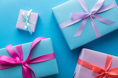 top view of colorful gift boxes with ribbons on blue background clipart