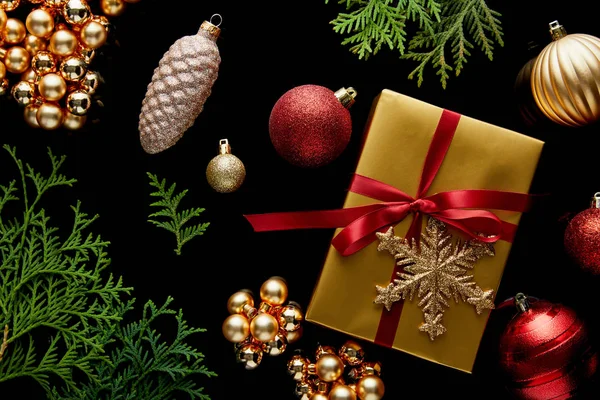 金光闪闪的圣诞装饰 绿色的Thuja枝条和装在黑色上的礼品盒的顶视图 — 图库照片