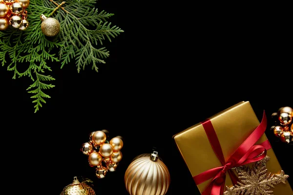 光沢のある黄金のクリスマスの装飾 緑のThujaの枝とギフトボックスのトップビューは黒に隔離された — ストック写真