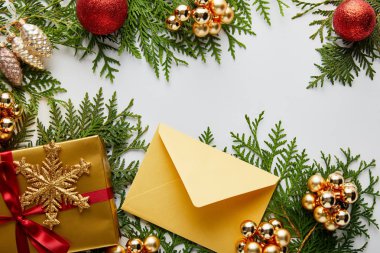 Parlak altın noel süslemesi, hediye ve zarf beyaza izole edilmiş yeşil thuja dalları