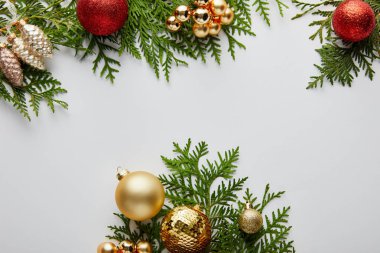 Beyaz üzerinde izole edilmiş yeşil thuja dalları üzerinde parlak altın ve kırmızı noel süslemeleri