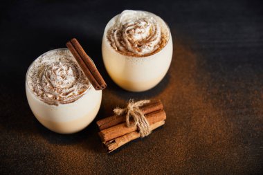 Krem şantili nefis eggnog kokteyli ve tarçın tozuyla kaplı tarçın çubukları.