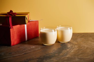 Lezzetli eggnog kokteyli ve portakallı koyu mermer masada hediye kutuları.