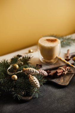 eggnog kokteyli şeker tozu, ladin dalları, tarçın çubukları ve turuncu arka planda noel süslemeleri ile kaplı masada.