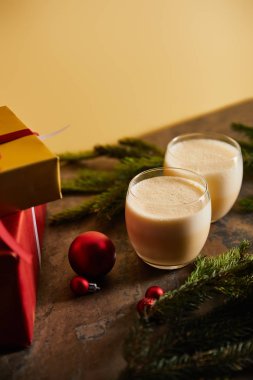 Geleneksel eggnog kokteyli, hediye kutuları, ladin dalları ve portakallı koyu mermer masa üzerindeki Noel topları.