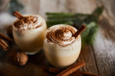Tahta masada tarçın çubuklarının yanında krem şantili nefis eggnog kokteylinin seçici odağı.