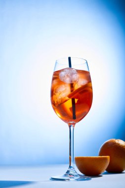 Bardakta saman ve mavi arka planda portakallı Aperol Spritz kokteyli. 