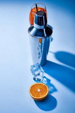 Aperol Spritz kokteylinin yüksek açılı görüntüsü, turuncu, titretici, mavi arkaplanda buz küpleri 