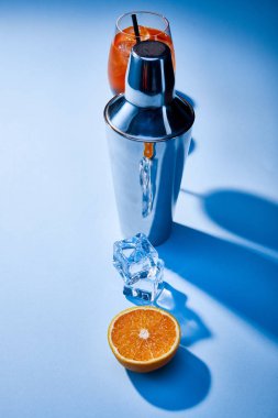 high angle view of cocktail Aperol Spritz, orange, shaker, ice cubes on blue background  clipart