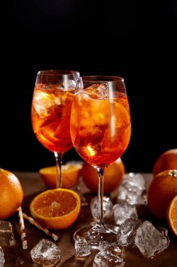 Siyah zemin üzerinde gözlüklü, portakallı ve buzlu Aperol Spritz. 