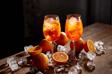 Siyah zemin üzerinde gözlüklü, portakallı ve buzlu Aperol Spritz. 
