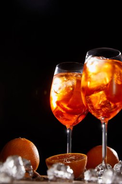 Siyah zemin üzerinde gözlüklü, portakallı ve buzlu Aperol Spritz. 