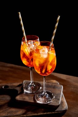 Aperol Spritz, tahta kesme tahtalarında pipetle bardaklarda.