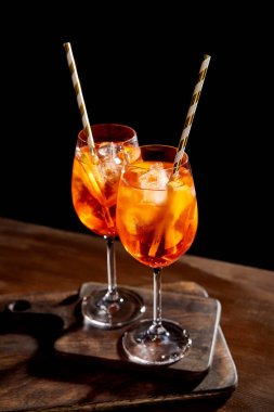 Aperol Spritz in glasses with straws on wooden chopping boards clipart