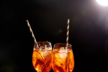 Siyah arka planda pipetli gözlüklü Aperol Spritz 
