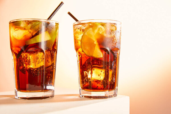 cocktails cuba libre in glasses with straws on cube  