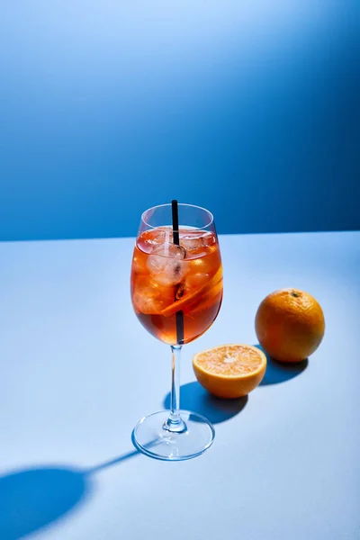 Aperol Spritz鸡尾酒 带玻璃杯的稻草和蓝色背景的橙子 — 图库照片