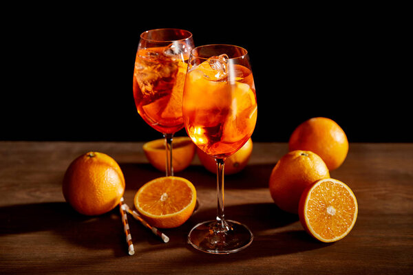 Aperol Spritz in glasses and oranges on black background 