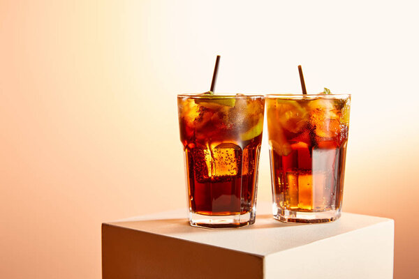 cocktails cuba libre in glasses with straws on cube  