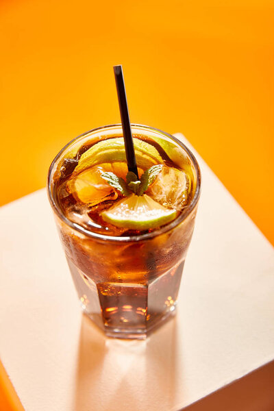 high angle view of cocktail cuba libre in glass with straw on cube 