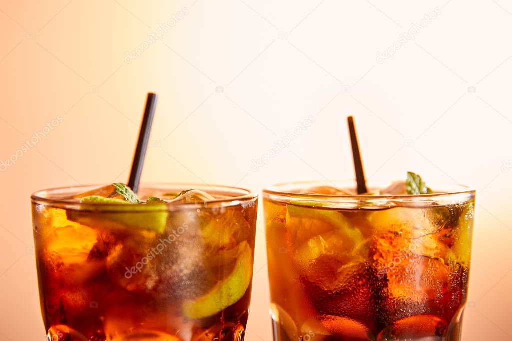 cocktails cuba libre in glasses with straws on beige background 