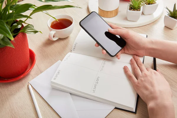 Vista Recortada Mujer Sosteniendo Teléfono Inteligente Cerca Sobre Cuaderno Con — Foto de Stock