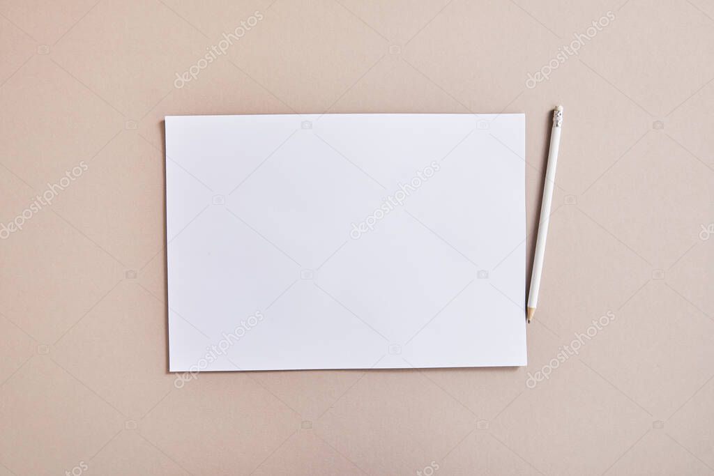 top view of blank white paper with pencil on beige surface