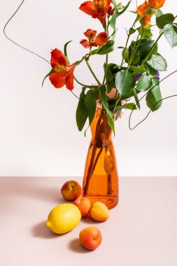 Gül ve kırmızı Alstroemeria çiçekli kompozisyon turuncu vazoda kablolar içinde limon ve kayısılar beyaz üzerinde izole edilmiş.
