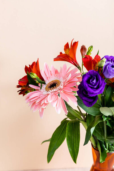 floral composition with bouquet in orange vase isolated on beige