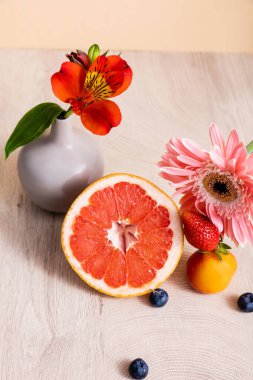 Alstroemeria, Gerbera, böğürtlen, greyfurt ve kayısı ile bej üzerine izole edilmiş ahşap yüzey.
