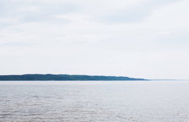 Bulutlu gökyüzüne karşı durgun ve mavi deniz 