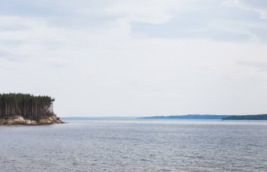 Yeşil ağaçların yanındaki temiz göl bulutlu gökyüzüne karşı 