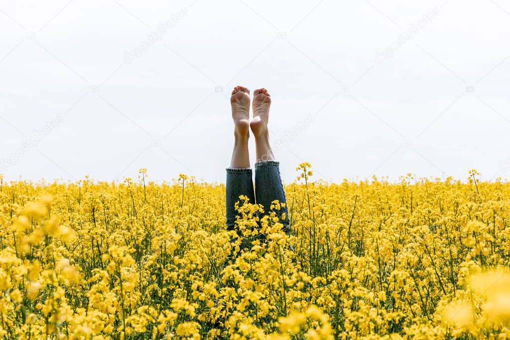 cropped view of barefoot woman near yellow flowers in field 